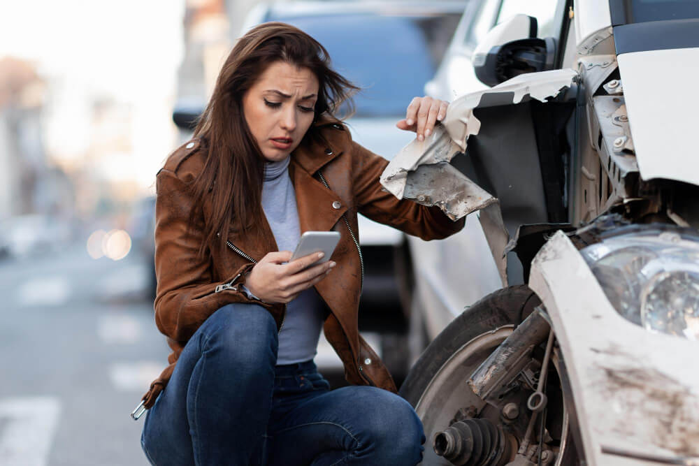 Woman checking phone after a car accident